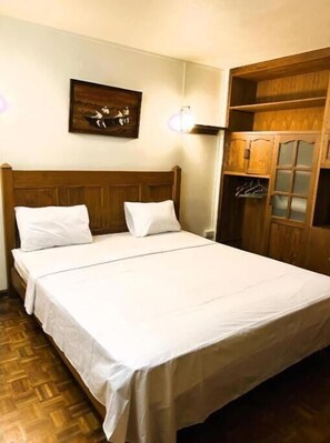 Restful retreat with a large bed, wooden wardrobe, and framed artwork.