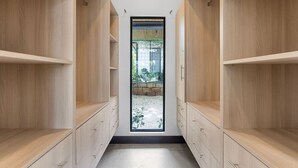 A narrow hallway with wooden shelving units on either side and a small window at the end.