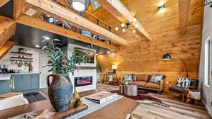 A spacious living area with a wooden ceiling, a dining table with a vase and book, and a sofa with cushions. - Secluded View! A-Frame Hot Tub and Fire Pit (Bryson City)