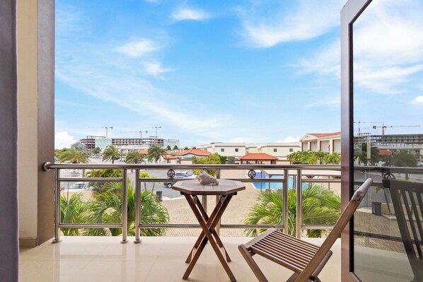 A balcony with a view of a residential area, a small table, and a chair.