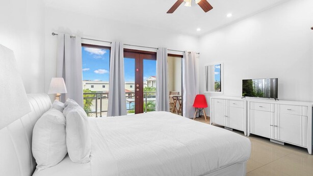 Une chambre d’hôtel équipée d’un lit, d’un ventilateur de plafond, d’une télévision, d’un bureau et offrant une vue sur l’extérieur.