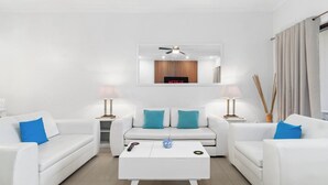 Un salon moderne avec un ensemble de canapés blancs, une table basse et un ventilateur de plafond.