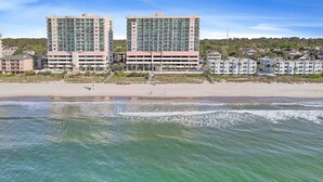 A beachfront hotel with multiple floors, a parking garage, and a sandy beach. - Crescent Keyes 904 - 3BD/3BA Oceanfront Condo (North Myrtle Beach)