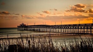 A pier extending into the water with a small structure at the end, surrounded by tall grasses. - Pet Friendly 3 BR House - Latitude Adjustment (North Myrtle Beach)