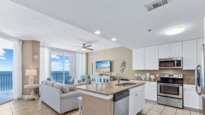 A modern kitchen with white cabinets, a granite countertop, and stainless steel appliances. - Lighthouse 1004 (Gulf Shores)