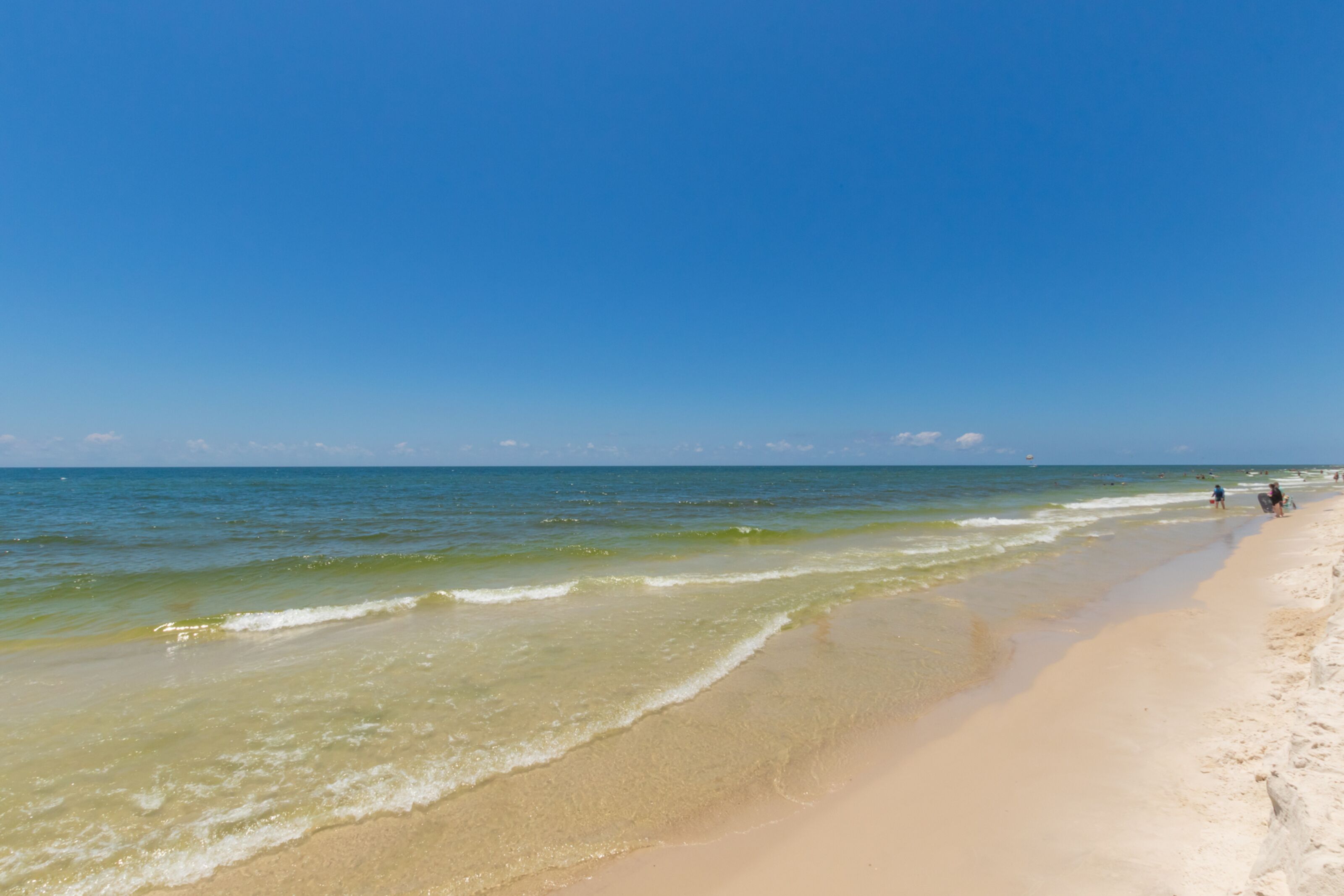 A beach with clear blue water and a sandy shore.