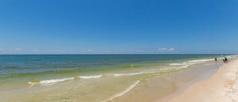 A beach with clear blue water and a sandy shore.