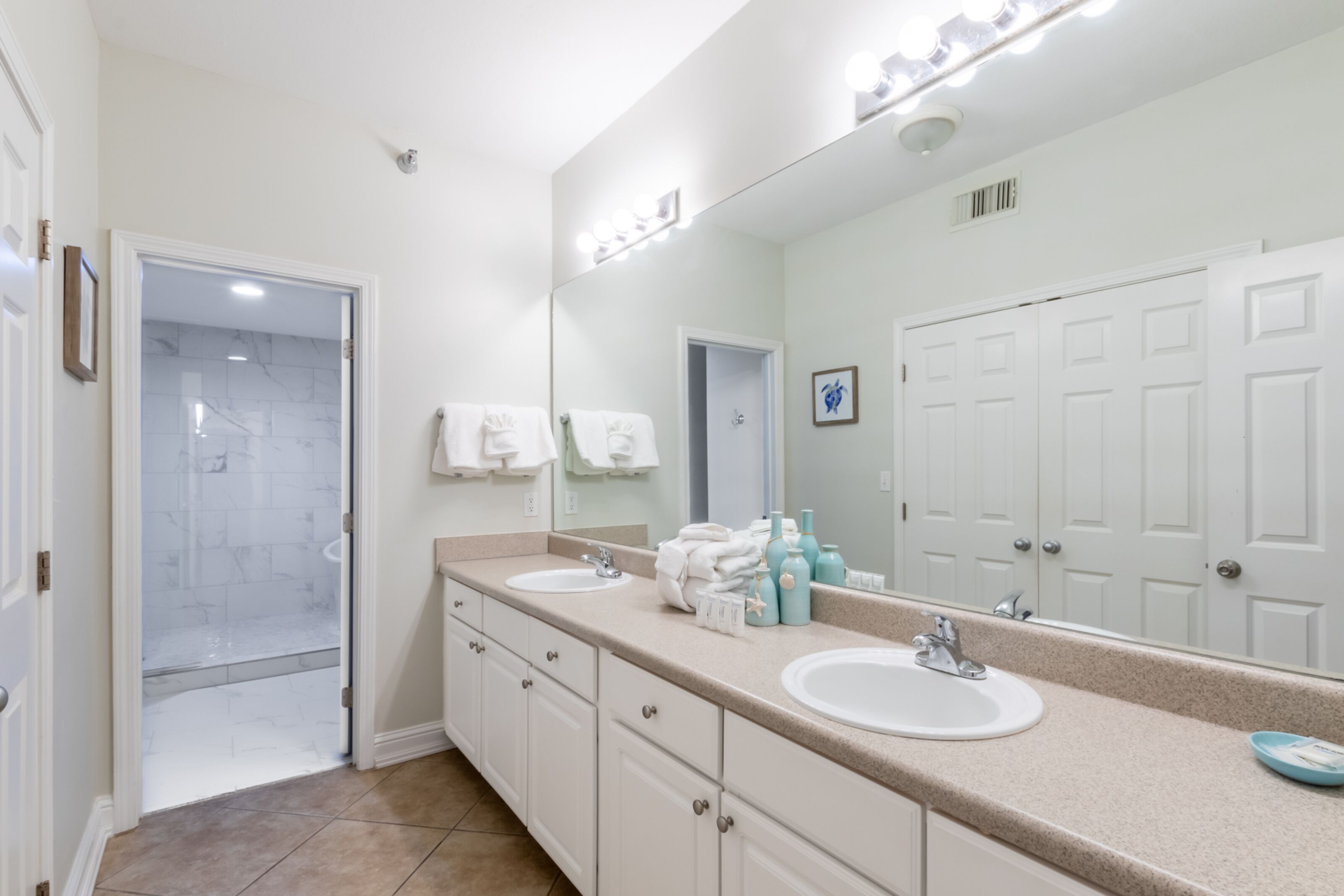 Une salle de bain avec deux lavabos, un grand miroir et un espace douche.