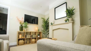 A living room with a sofa, a TV mounted on the wall, a fireplace, and a bookshelf with decorative items. - Close to Castle | Free Wi-Fi | Close to Cathedral (Lincoln)