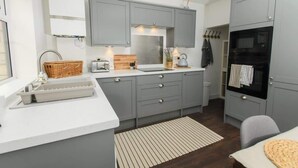 A compact kitchen with grey cabinets, a white countertop, a built-in oven, and a small dining area. - Close to Castle | Free Wi-Fi | Close to Cathedral (Lincoln)