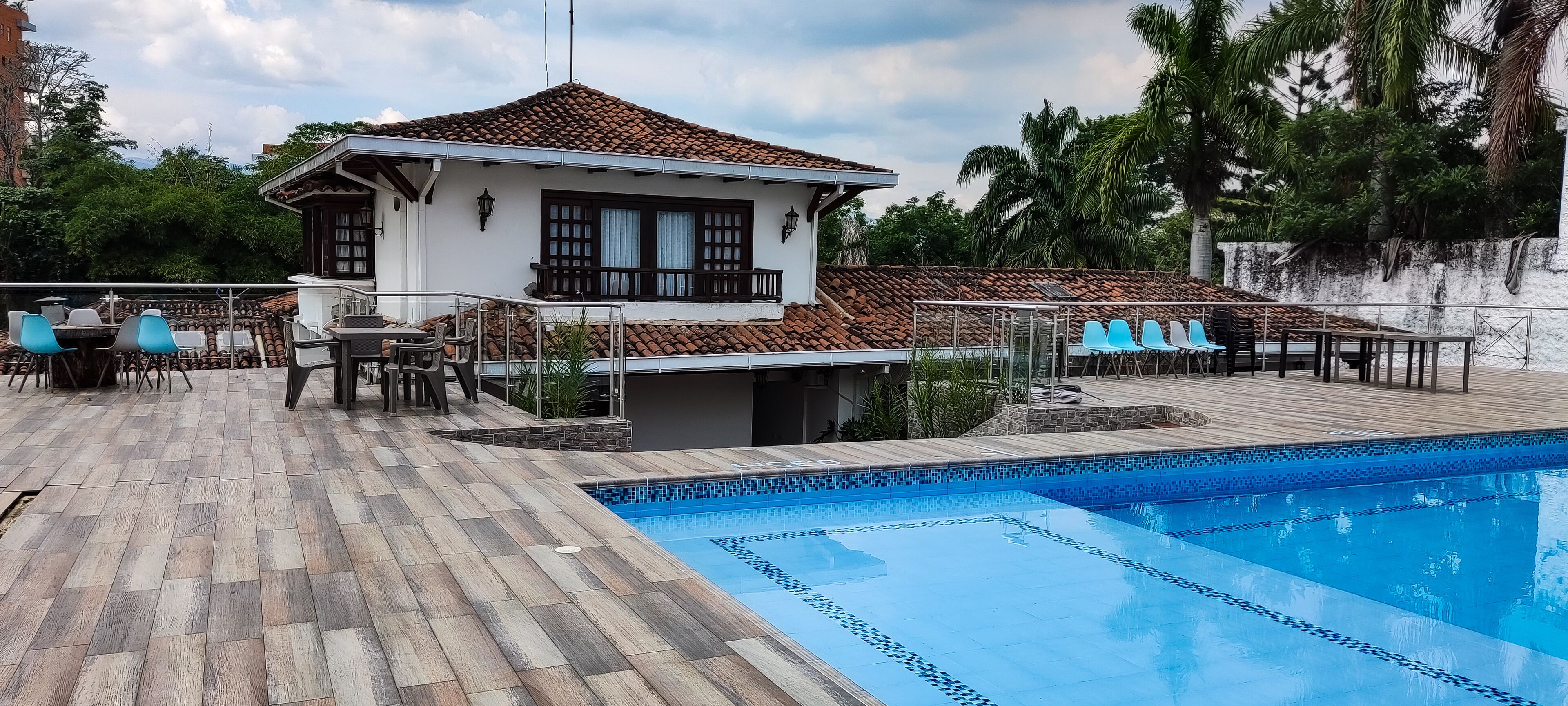 Una casa con piscina, un patio con sillas y vistas del entorno.