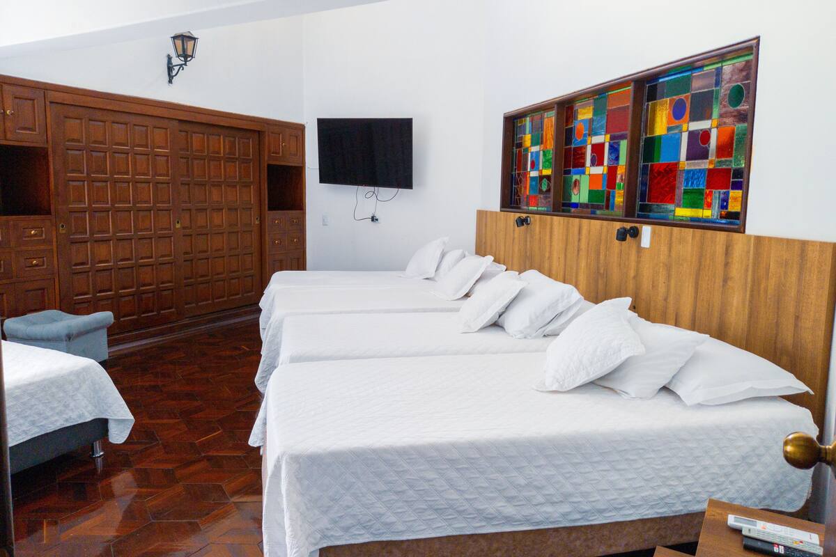 Una camera d'albergo con un armadio in legno, una televisione a muro e una finestra a vetri colorati.