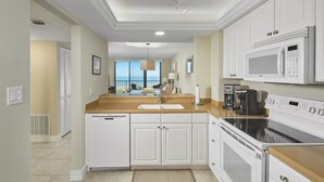 Une cuisine moderne avec des meubles blancs, un four à micro-ondes encastré, une cuisinière et une machine à café.