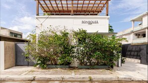 A modern building with a wooden pergola, greenery, and the text "SONSOLEA HOST" on the facade. - Sonsoleá Host (Luquillo)