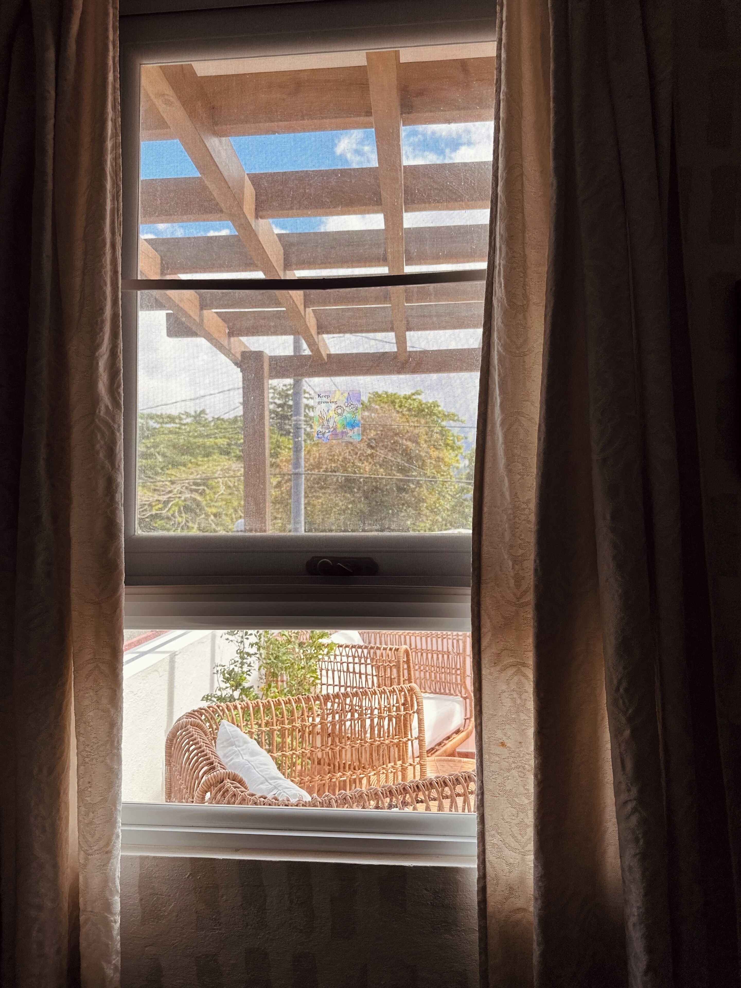 Ventana con vista a una pérgola de madera y mobiliario exterior.