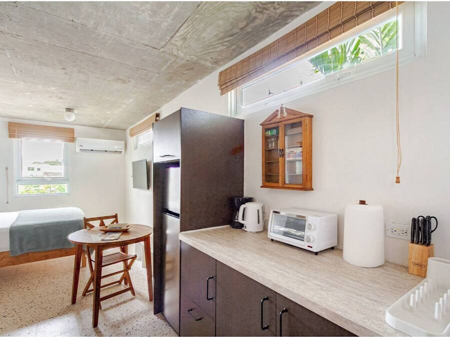 Una cocina compacta con refrigerador, microondas, tostadora y mueble de madera.