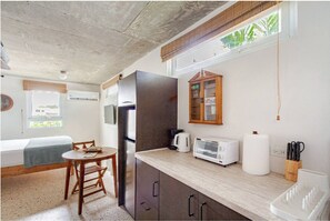 Una cocina compacta con refrigerador, microondas, tostadora y mueble de madera.