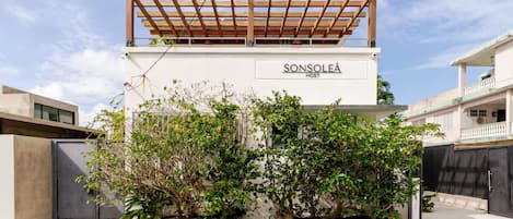 A modern building with a wooden pergola, greenery, and the text "SONSOLEA HOST" on the facade.