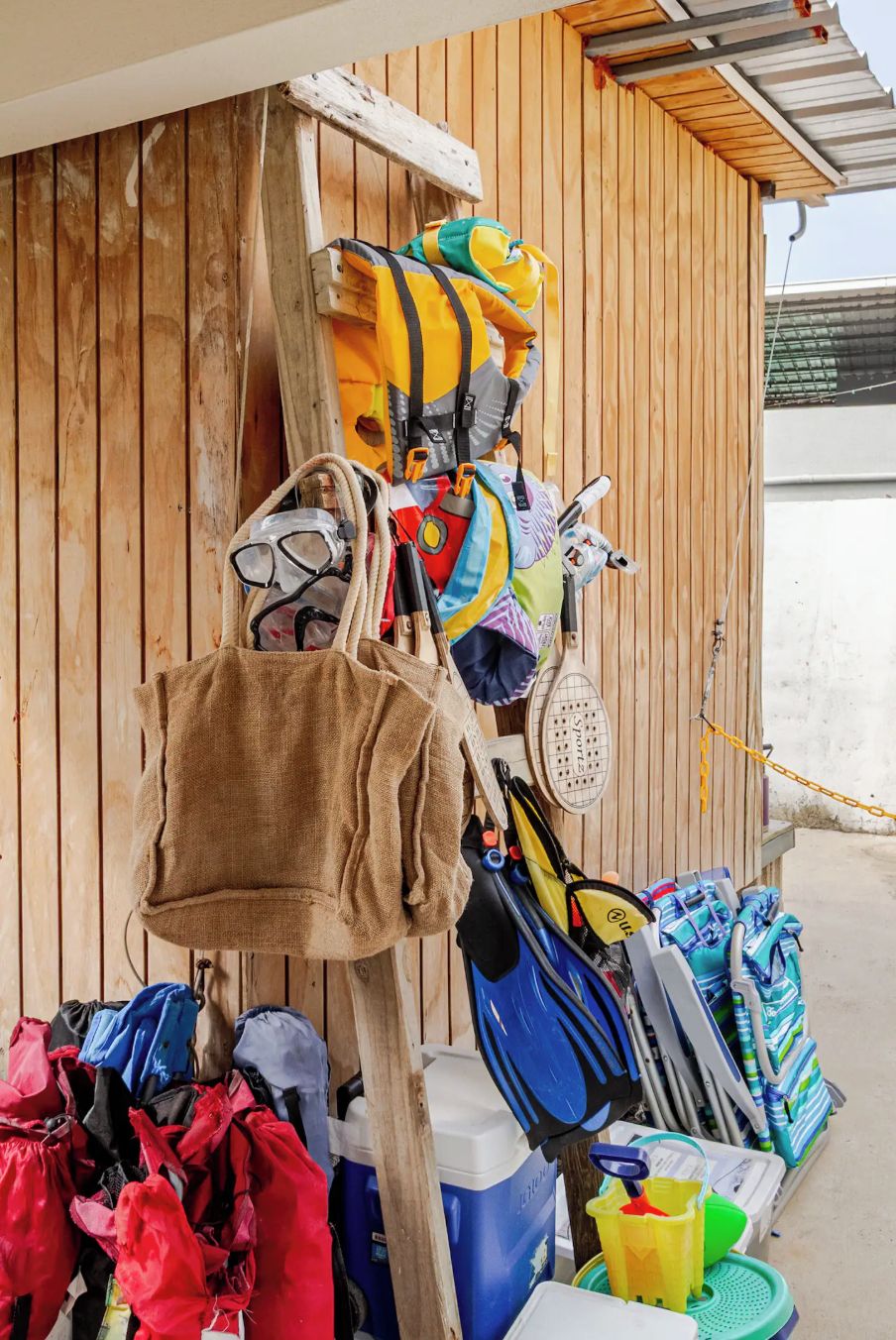 Una estructura de madera con varias bolsas y equipo colgando, incluyendo una bolsa marrón, una bolsa amarilla y una bolsa azul.