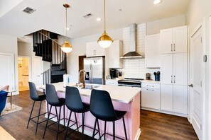 A modern kitchen with a central island, bar stools, and a staircase. - West End 4 Bd/4Bath Walk to Bars-Close to Broadway (Nashville)