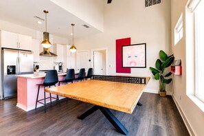 A modern kitchen with a central island, pendant lighting, and a dining area with a table and chairs. - West End 4 Bd/4Bath Walk to Bars-Close to Broadway (Nashville)