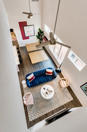 A modern living room with a blue sofa, a round coffee table, and a ceiling fan. - West End 4 Bd/4Bath Walk to Bars-Close to Broadway (Nashville)