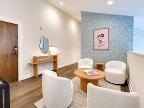 A modern interior with a wooden door, a wall-mounted mirror, a round wooden table, and two white armchairs. - West End 4 Bd/4Bath Walk to Bars-Close to Broadway (Nashville)