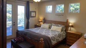 Une chambre à coucher avec un lit, des tables de chevet, un ventilateur de plafond et des fenêtres.