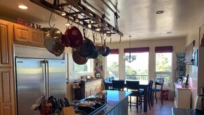La cuisine est équipée d’un réfrigérateur en acier inoxydable, d’une cuisinière et de casseroles suspendues. On y trouve également un coin repas avec une table et des chaises.