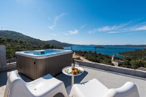 A hot tub with a table and chairs on a terrace overlooking a body of water and hills. - Cluster Villas Vucetic (Sali)