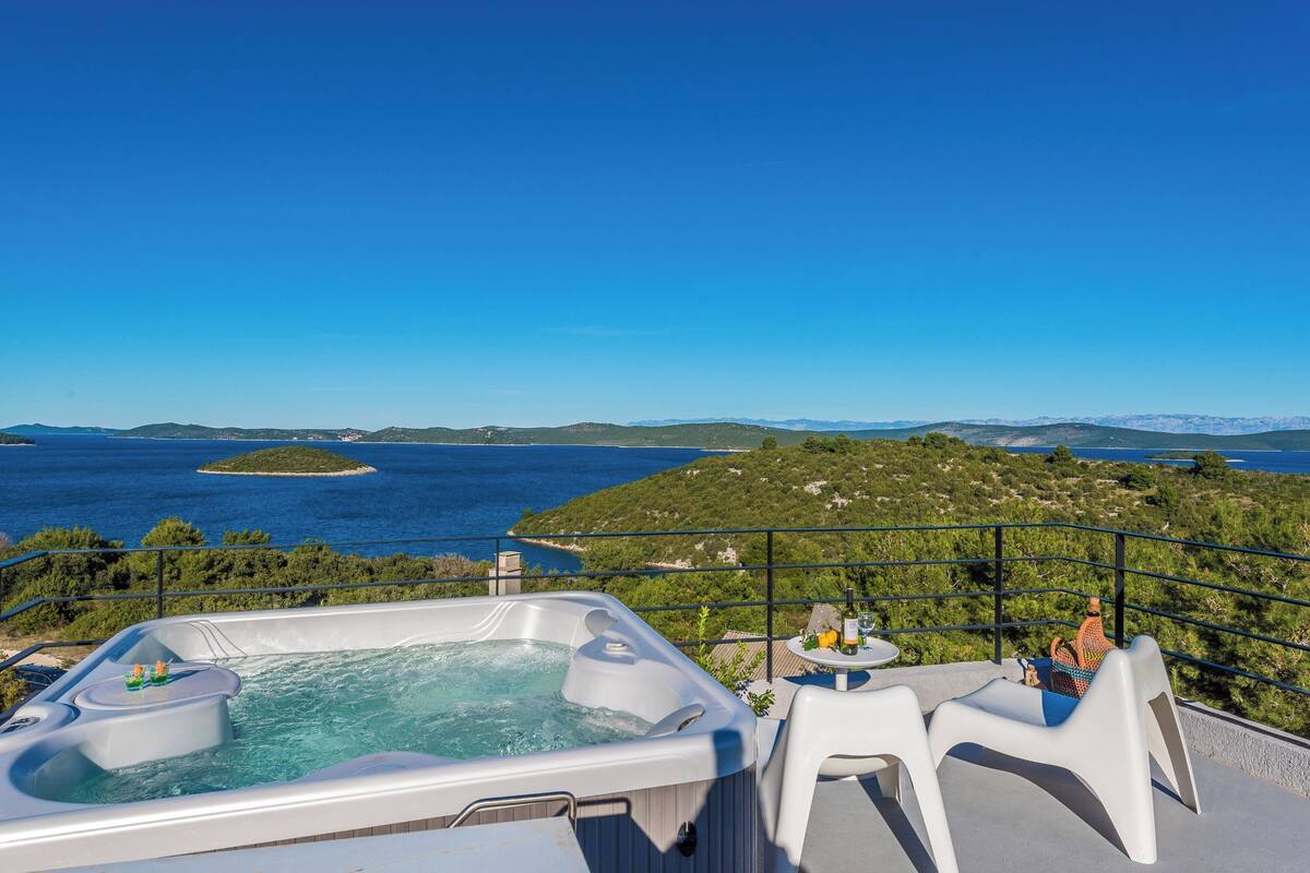 Uma banheira de hidromassagem com vista clara para o mar e ilhas.