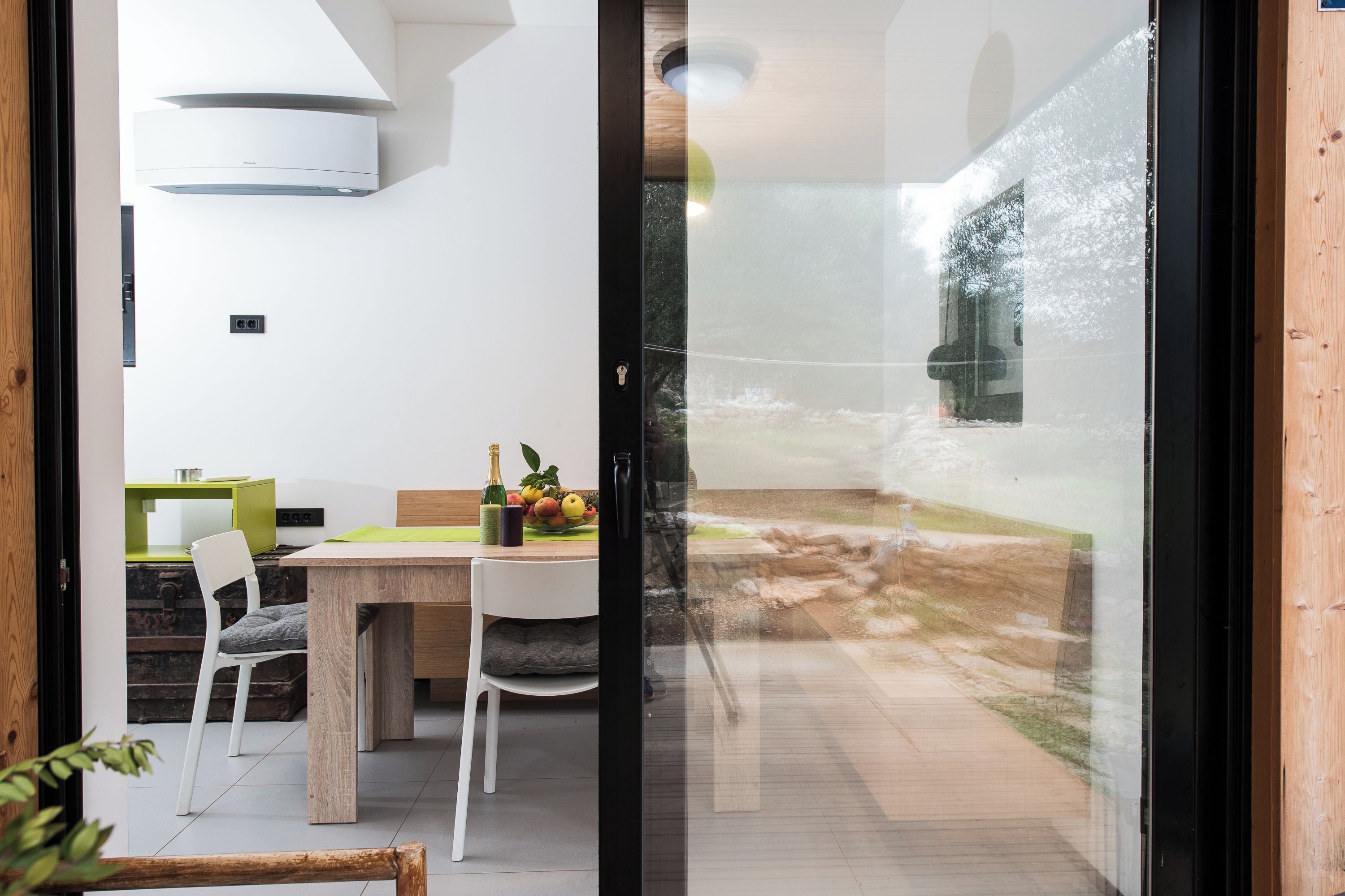 Una cocina moderna con comedor, aire acondicionado integrado y vista al patio trasero a través de un ventanal.
