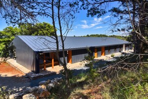 A modern building with a sloped roof, wooden beams, and a stone foundation. - Cluster Villas Vucetic (Sali)