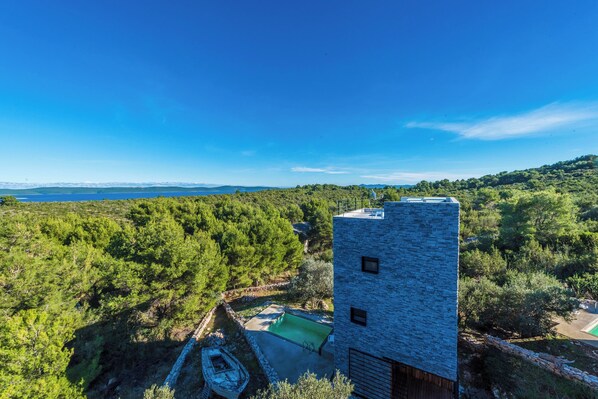 A modern building with a stone facade, surrounded by lush greenery and a clear blue sky. - Cluster Villas Vucetic (Sali)