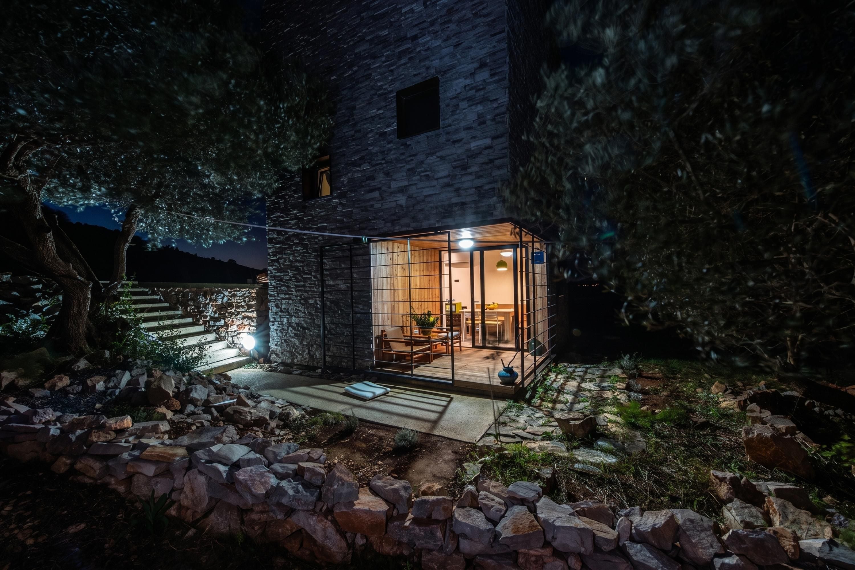 A modern house with a stone exterior, a glass door entrance, and a patio area with outdoor furniture.