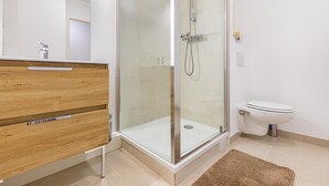 Ein modernes Badezimmer mit einer gläsernen Duschkabine, einem Holzwaschtisch und einer weißen Toilette.
