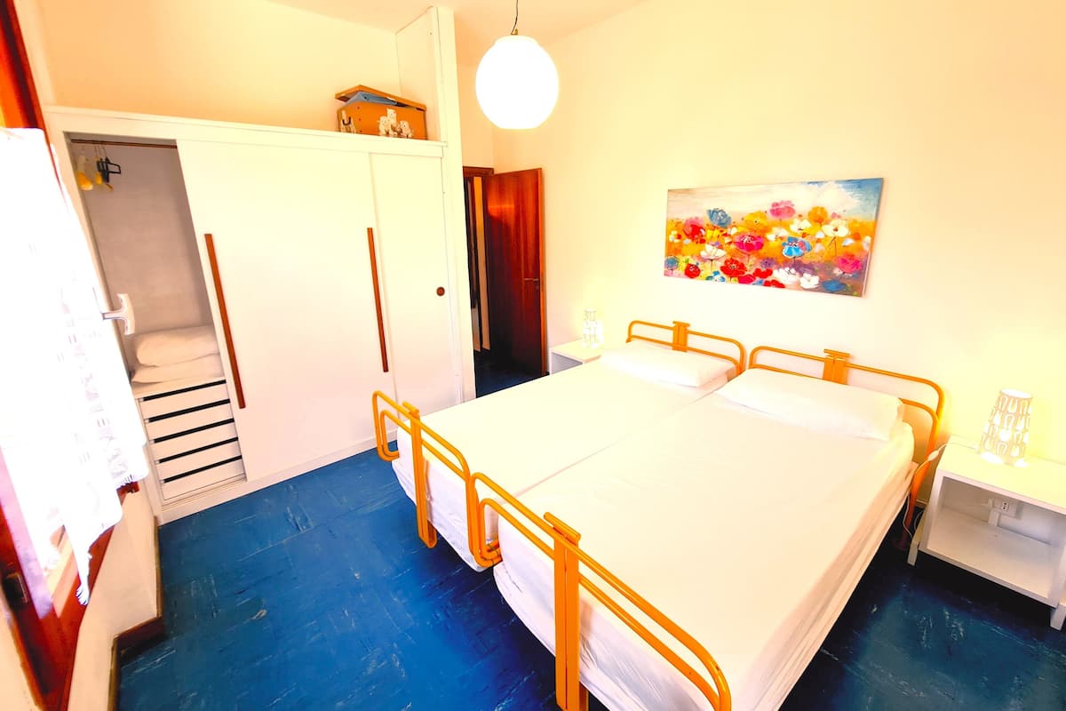 A bedroom with a bed, a wardrobe, a painting, and a bedside table.