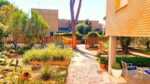 Um jardim com um caminho pavimentado, plantas em vasos e área de estar ao ar livre.