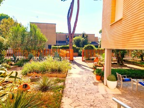 A garden with a paved walkway, potted plants, and outdoor seating. - Casa Pineta (Grosseto)