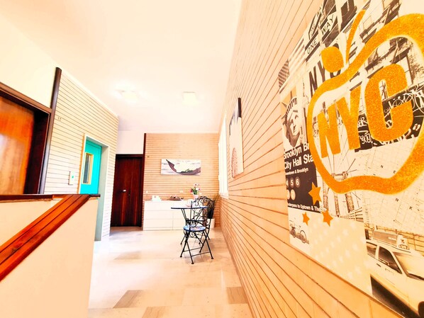 A hallway with a wooden floor, a desk with a chair, and a wall with a large NYC-themed poster. - Casa Pineta (Grosseto)