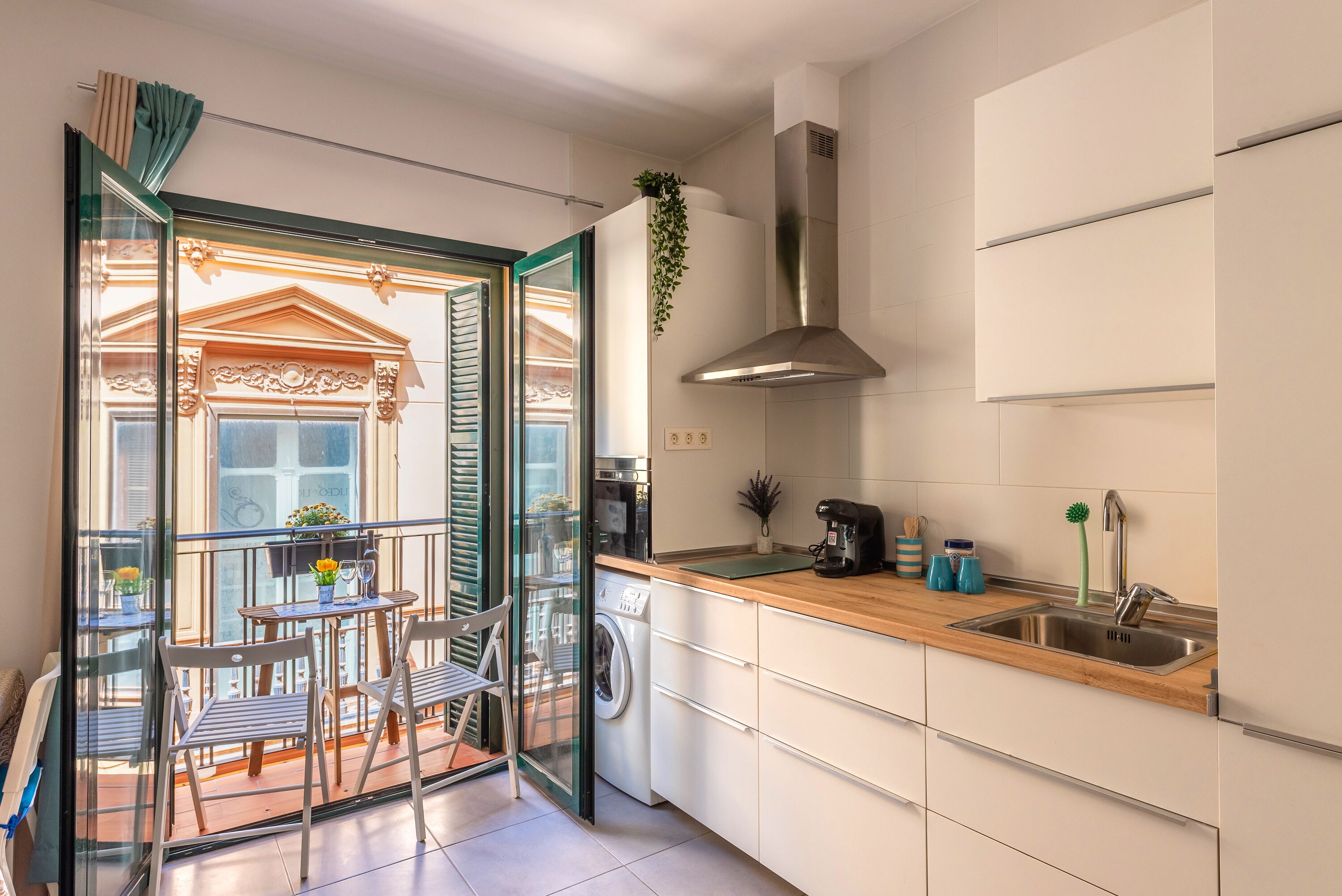 A modern kitchen with a built-in washing machine, a stainless steel sink, and a wooden countertop.
