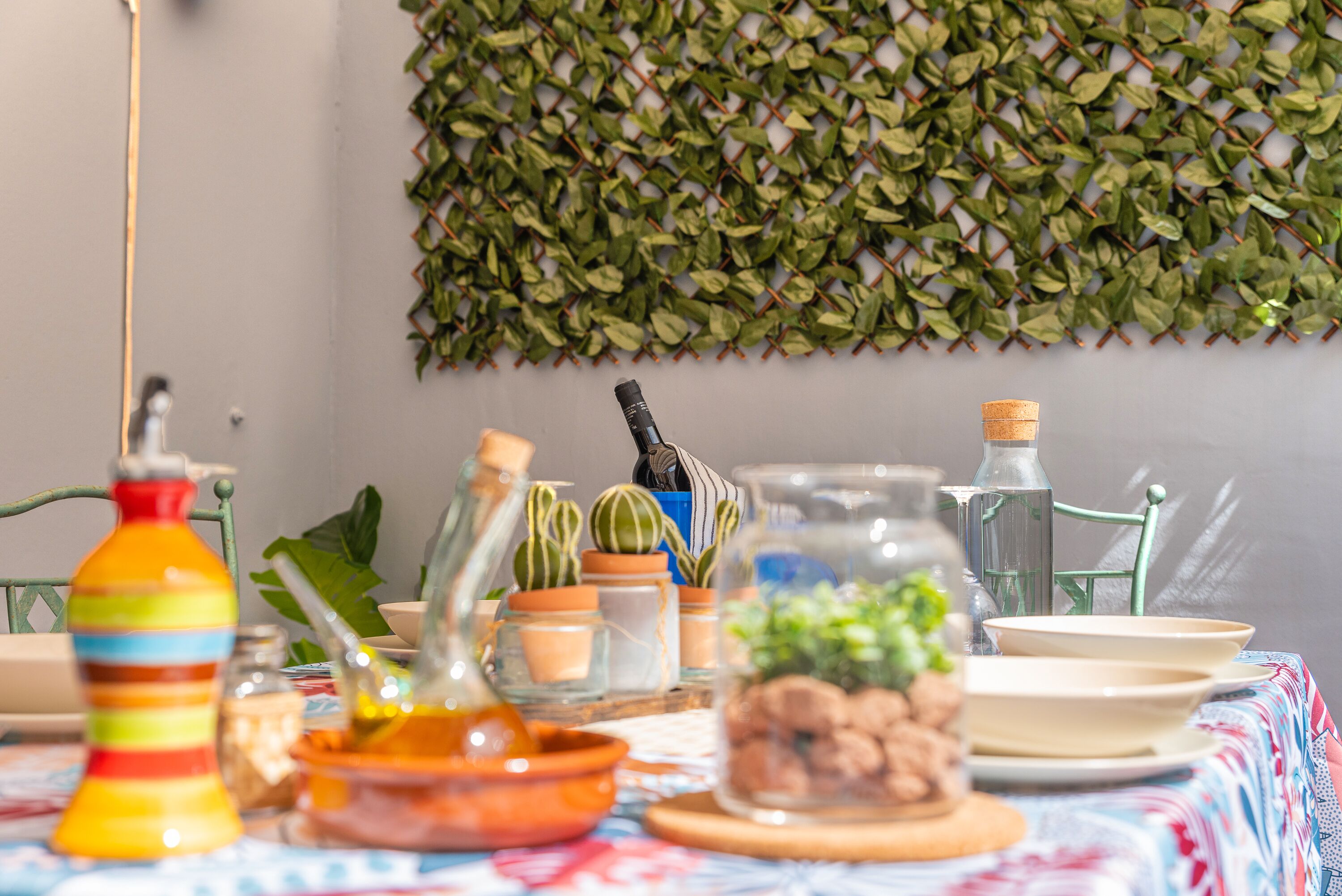 A dining table with various items including a striped bottle, glass jars, and potted plants.