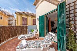 A balcony with two sun loungers, a potted plant, and a view of neighboring buildings. - Skysea Holidays City Center Suites (Málaga)