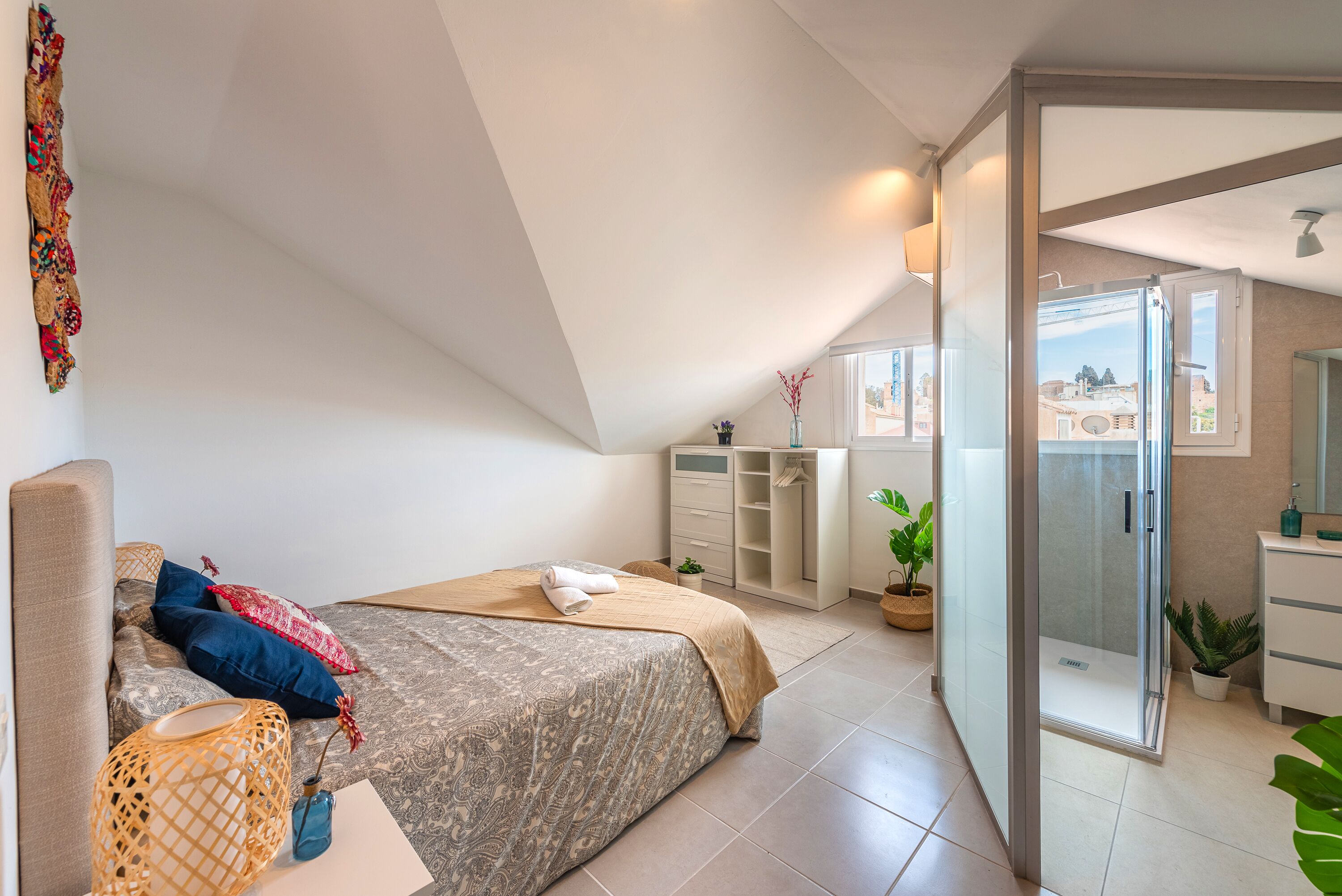 Ein modernes Schlafzimmer mit einem großen Bett, einem begehbaren Kleiderschrank und einem Badezimmer mit Glasdusche.