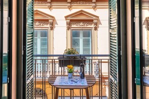 A balcony with a table, a bottle, and a vase of flowers. - Skysea Holidays City Center Suites (Málaga)