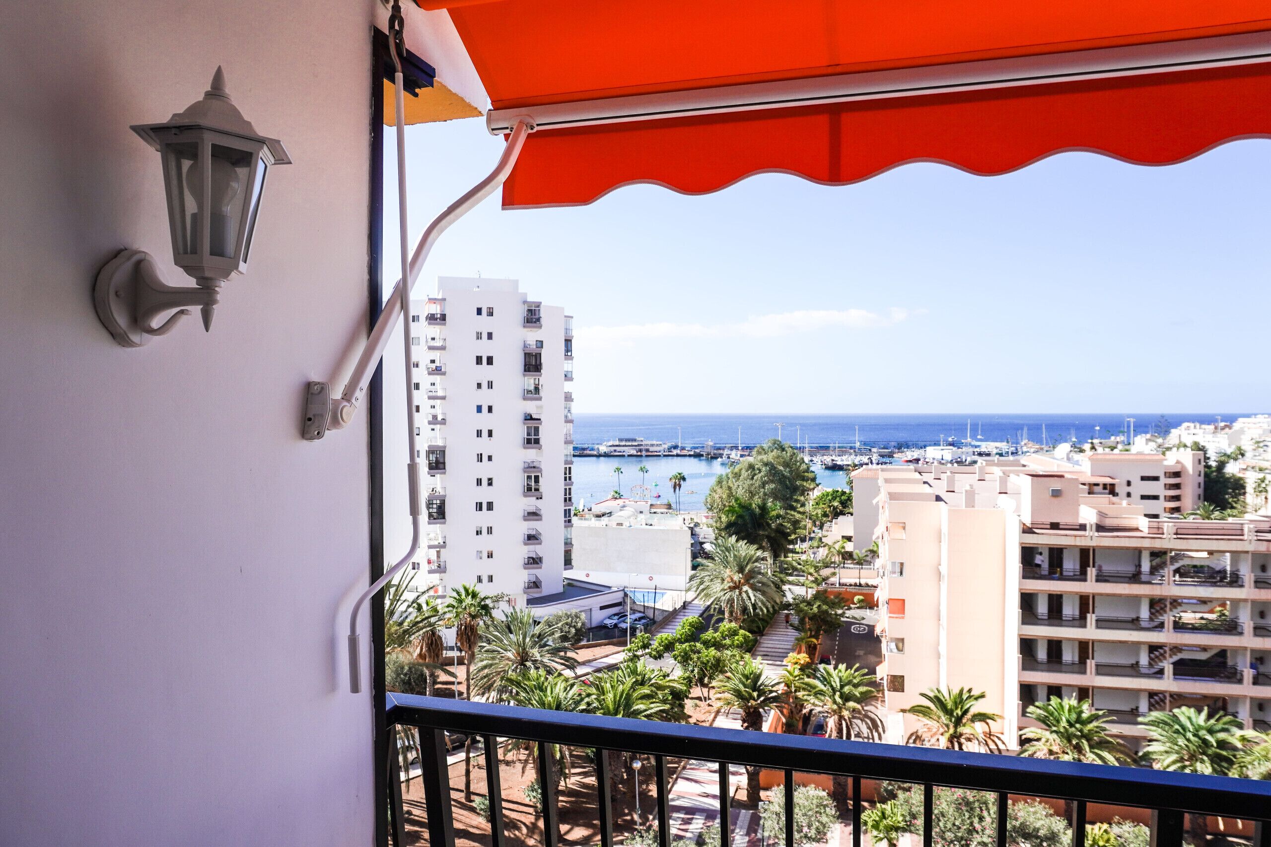 Un balcón con vistas a un puerto deportivo, edificios y palmeras.