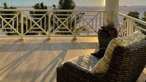Un balcon fermé offrant une vue sur la mer au coucher du soleil.