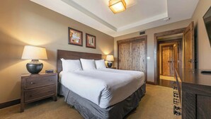 Un dormitorio ordenado con una cama grande, dos mesitas de noche con lámparas, un armario de madera y cuadros en la pared.
