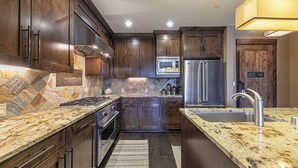 Una cocina moderna con armarios de madera oscura, electrodomésticos de acero inoxidable y una encimera de granito.