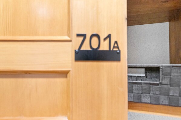 Una puerta de madera con un letrero negro que muestra el número '701A'.